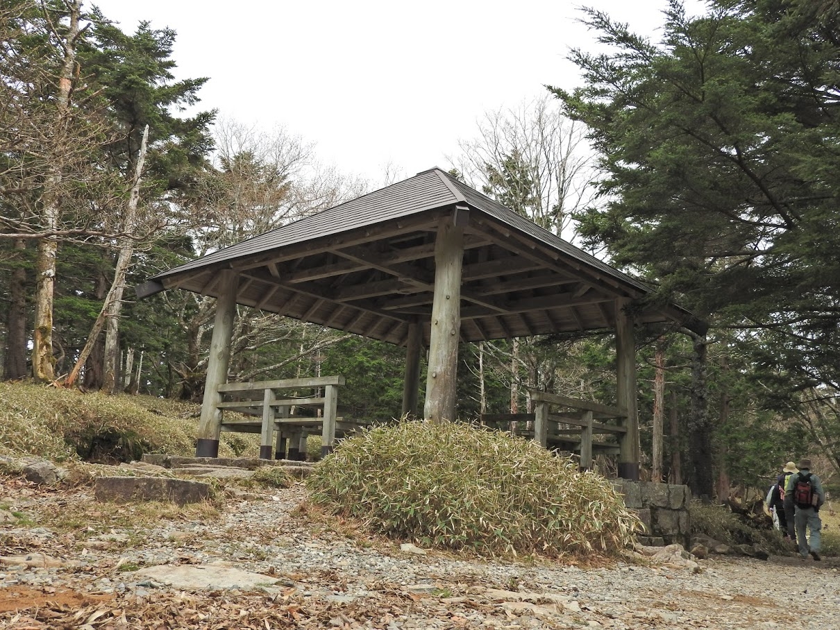 周囲に木々が生えた登山道沿いに木製の東屋が設置されている尾鷲辻の写真