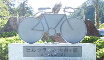 「ヒルクライム大台ヶ原since2001」の文字と石で作られた自転車のモニュメントの石碑の写真