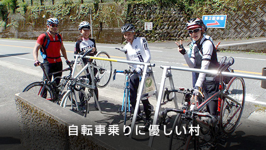 「自転車乗りに優しい村」自転車の横でヘルメットを着用した参加者4人が笑顔で写っている写真