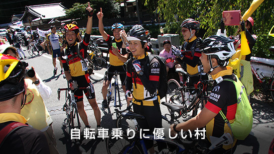 「自転車乗りに優しい村」自転車の横でヘルメットを着用した参加者たちがポーズを決めて撮影している様子の写真