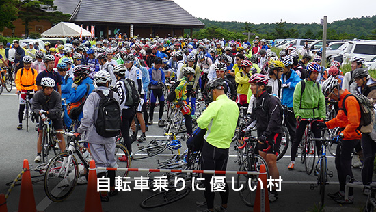 「自転車乗りに優しい村」ヒルクライムレースに参加するヘルメットを着用した選手たちが集まっている様子の写真