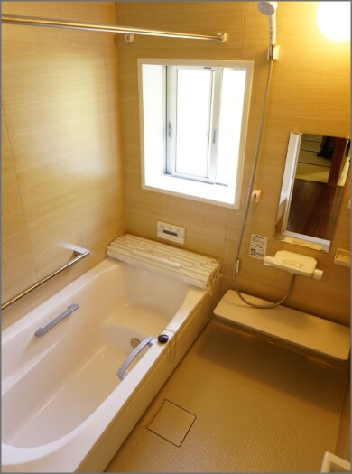 明かりの差し込む窓が設置された、浴室乾燥機がついた白を基調とした浴室内部の写真