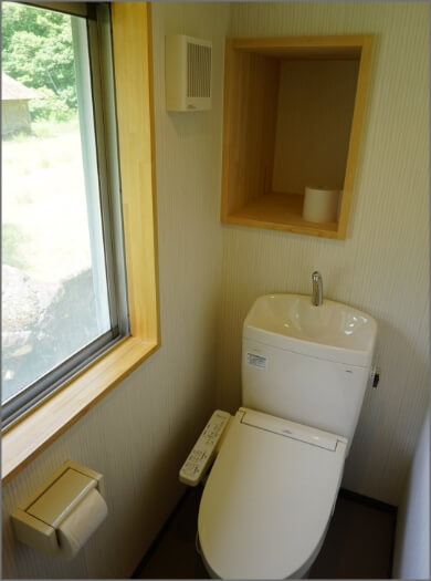 左の窓から日が差し込む、洋式トイレが設置された写真